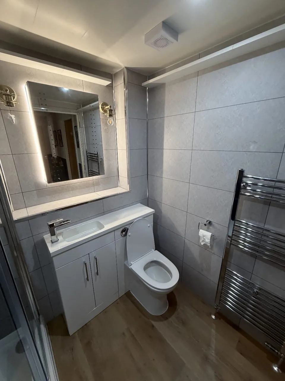 White bathroom furniture and a large illuminated mirror